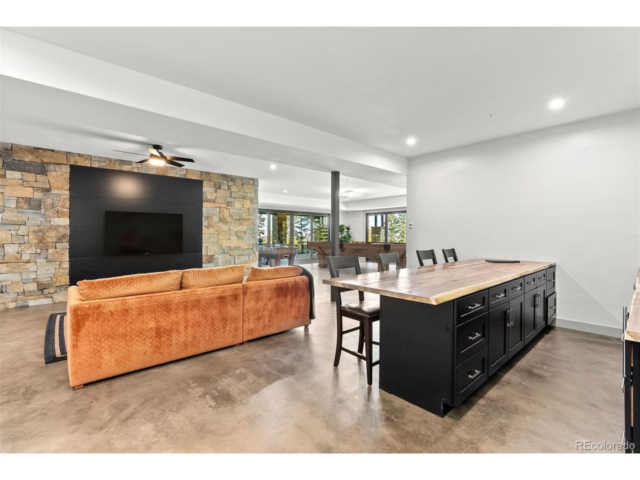 A spacious lower-level room is designed for entertaining, featuring a full bar, room for games, and multiple seating zones