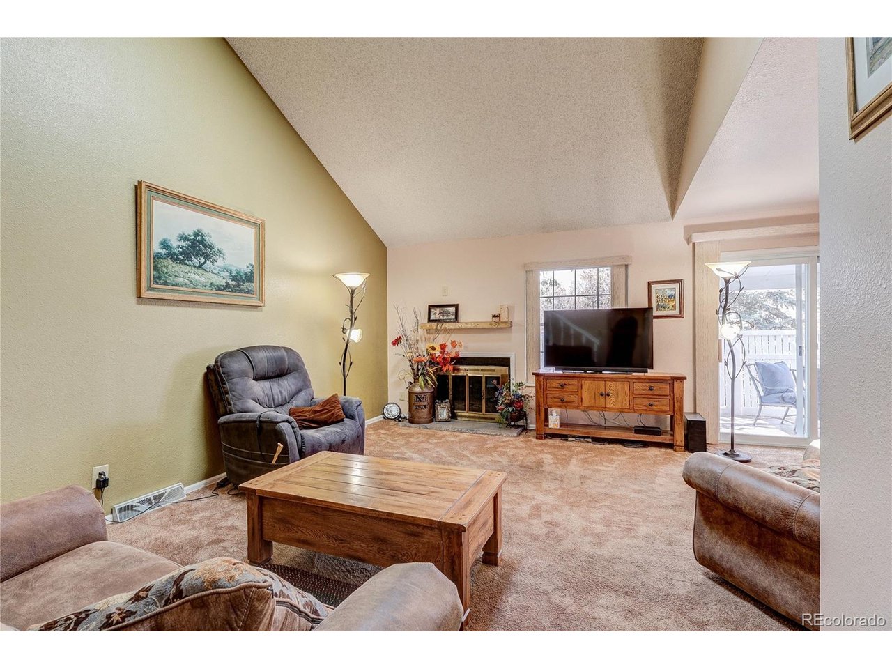 Looking west, the vaulted living room has a wood burning fireplace, newer windows and sliding doors