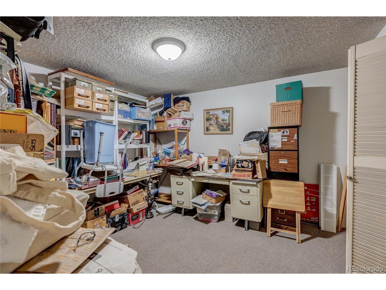 One very filled basement bedroom used as an office