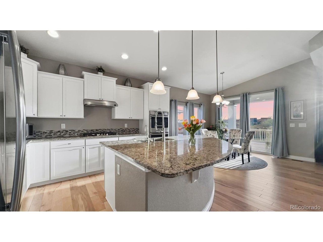 Island Kitchen with granite countertops, breakfast bar, pendant lights, and stainless steel appliances.