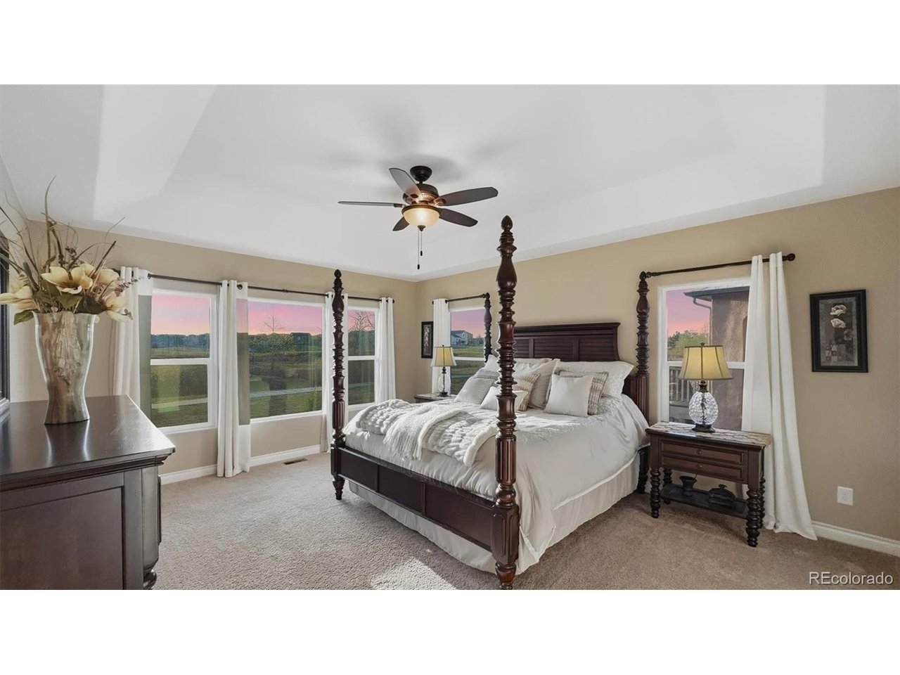 Primary Bedroom with neutral carpet, a lighted ceiling fan, wall of windows, walk in closet, and 5pc Spa Bathroom.