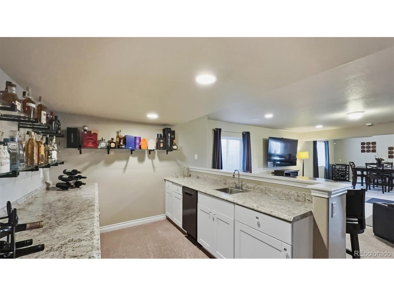 Basement wet bar with granite countertops, dishwasher, wine fridge, and beverage refrigerator.