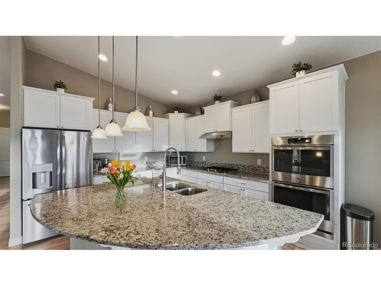 Gorgeous curved granite island in Kitchen with breakfast bar and pendant lights.