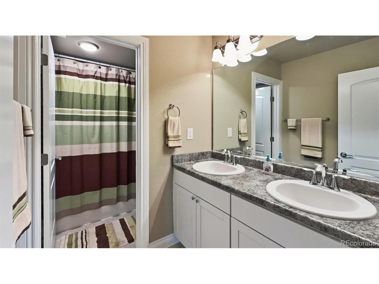 Basement Full Bathroom with dual sink vanity, mirror, and tiled tub/shower.