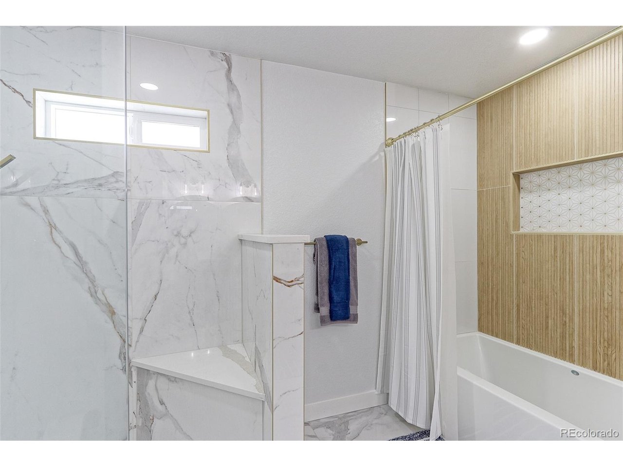 This bath has 2 showers that include a massive walk-in shower with marble tile surround, frameless glass enclosure and custom dual shower heads, plus another oversized tub with shower that features designer tile surround as well.