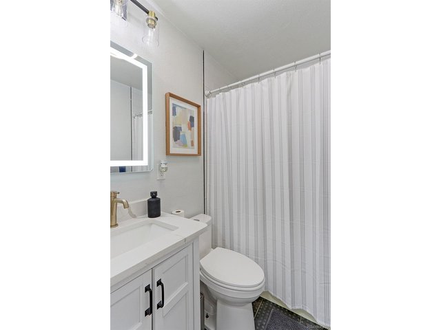 Property Photo 19 There is a completely renovated main floor full guest bath with designer tile floors, a custom vanity with quartz counter with integrated sink, spacious tub with shower that has designer subway tile surround with built-in shelf nook and all new fixtures an