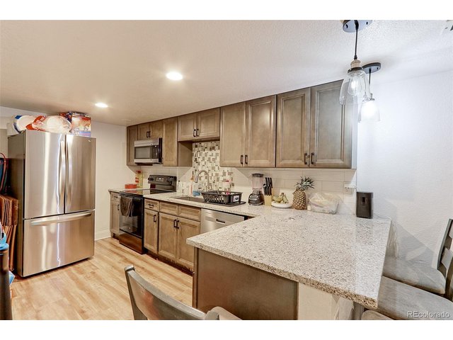 Property Photo 22 The 12x8 basement kitchen features LVP flooring, custom glazed raised panel cabinets with designer bronze pulls, solid granite countertops, designer tile backsplash, double deep stainless-steel integrated sink and upgraded stainless appliances that include