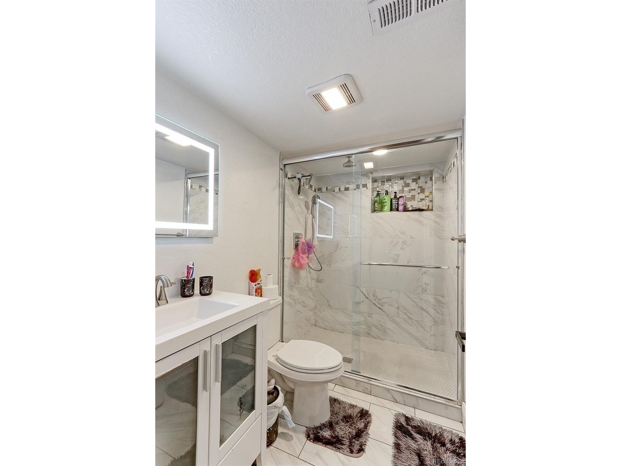There is a completely renovated 3/4 bath in the basement that features oversized marble tile floors, a custom vanity with large integrated sink plus a walk-in shower with glass enclosure, marble tile surround and 3 shower heads, that include, a wand and ra